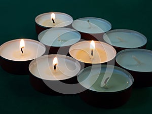 Short candles are burning against a dark background. Lots of small candles. Extinguished