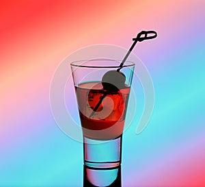 Short drink glass with red liquid and green olive