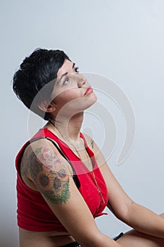 Short-hair brunette woman looking up wearing a red tank top