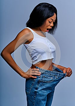Short-haired woman stares in surprise at her jeans after losing weight. Diet concept