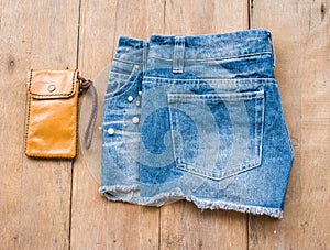 Short jean with leather bag on wood background