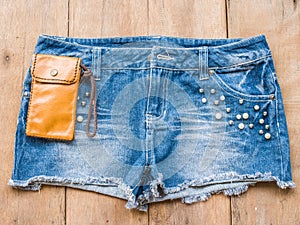 Short jean with leather bag on wood background