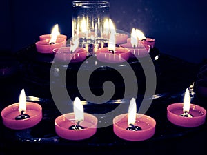 Short Lit Religious Candles In Dull Light