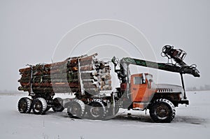 Short log truck in the snow, timber truck, loading logs in winter. manipulator loader logs