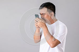 Short or long sighted concept : Man trying to look closer on smarthphone in studio shot on grey