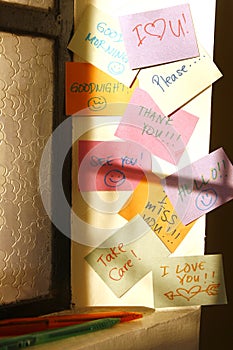 Short messages on colorful paper stuck on a wall by a window