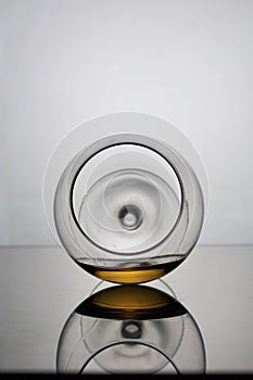 Short-stemmed wine glass. Lies on its side, photographed in the light. It has a small amount of alcohol