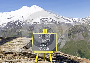 Short term debt cycle symbol. Concept words Short term debt cycle on beautiful black chalk blackboard. Beautiful mountain Elbrus