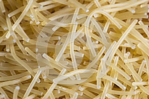 Short thin vermicelli on the whole background. texture of dry yellow pasta