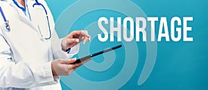 Shortage theme with a doctor using a tablet