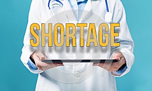 Shortage theme with a doctor using a tablet pc