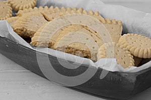 Shortbread biscuits cookies on greaseproof paper in a wooden bowl.