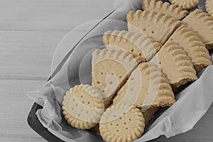 Shortbread biscuits cookies on greaseproof paper in a wooden bowl.