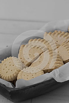 Shortbread biscuits cookies on greaseproof paper in a wooden bowl.