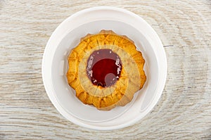 Shortbread cookie with jam in saucer on wooden table. Top view