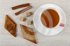 Shortbread cookies with cinnamon zemelakh, cinnamon sticks, sugar, cup of tea on saucer on table. Top view