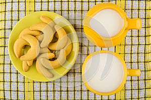 Shortbread cookies in saucer, jug milk and yellow cup