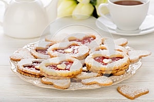 Shortbread cookies in the shape of heart with strawberry jam on wooden table.