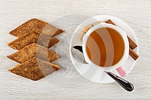 Shortbread cookies with sugar, cinnamon zemelakh, sugar cubes, spoon, cup of tea on saucer on table. Top view