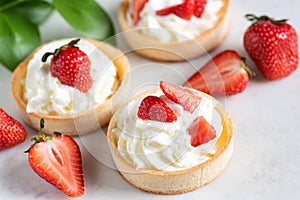 Shortcrust mini tarts with whipped cream and strawberries