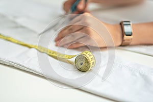 Shortening jeans. White jeans, Measuring tape, scissors on table. Jeans cutting.