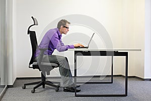 Shortsighted businessman bad sitting posture at laptop
