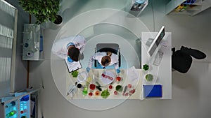 In the shot above, a woman sits and conducts an experiment spooning tomatoes. Then a man comes up and talks to her about