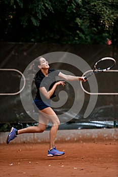 shot of active female tennis player hitting tennis ball with tennis racket