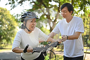 Shot of active senior couple riding bicycles in public park together. Healthy lifestyle concept.