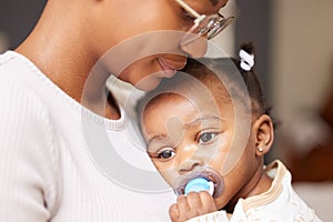 Shes getting tired now. Shot of an adorable baby girl sucking a dummy while being held by her mother at home.