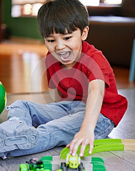 Little boys simply love trains, planes, trucks and cars. Shot of an adorable little boy playing with toys at home.