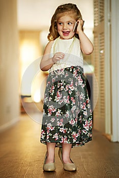 Shes an adorable little busy bee. Shot of an adorable little girl playing dress-up at home.