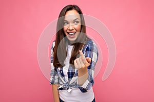 Shot of adult happy smiling beautiful brunette woman with sincere emotions wearing trendy check shirt isolated on pink