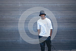 Shot of an African man with white t shirt and a black hat posing for the camera in the street, Spain