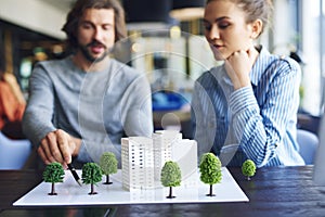 Architectural model and young adults architects in the background