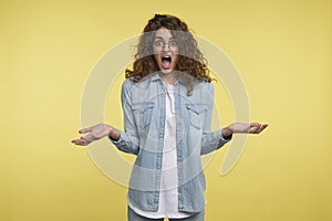 A shot of astonished young brunette woman, isolated over yellow background