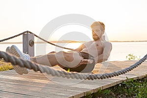 A shot of an athlete doing sit-ups outside.