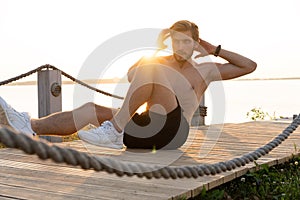 A shot of an athlete doing sit-ups outside.