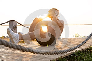 A shot of an athlete doing sit-ups outside.