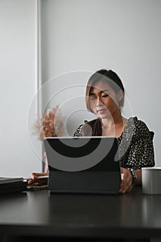 Shot of an attractive businesswoman is working on computer tablet in her workstation.