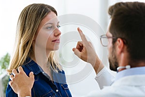 Attractive male doctor ophtalmologist checking the eye vision of beautiful young woman in modern clinic. photo