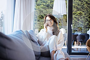 Shot of an attractive woman using her mobile phone and talkig with somebody while relaxing at home