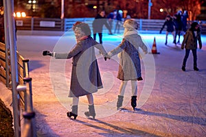 A shot from the back of two female friends while skating at ice-skating rink during Christmas holidays in the city. Christmas, New