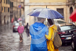 Shot from back of a young couple in love who is walking the city on a rainy day. Walk, rain, city, relationship