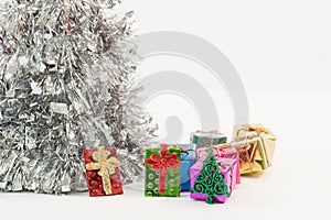 Shot of beautiful colorful gift boxes under the lush silver Christmas tree, festive mood