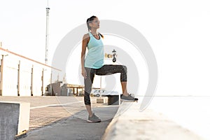Shot of beautiful female runner standing outdoors holding water bottle. Fitness woman taking a break after running