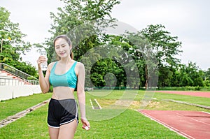 Shot of beautiful female runner standing outdoors holding water bottle. Fitness woman taking a break after running workout