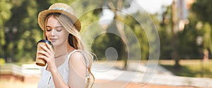 Shot of beautiful girl in white dress and straw hat holding paper cup and drinking coffee with closed eyes