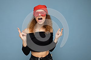 Shot of beautiful happy young dark blonde curly woman isolated over blue background wall wearing casual black crop top
