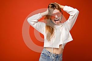 Shot of beautiful positive young blonde woman isolated over colourful background wearing white hoodie and stylish